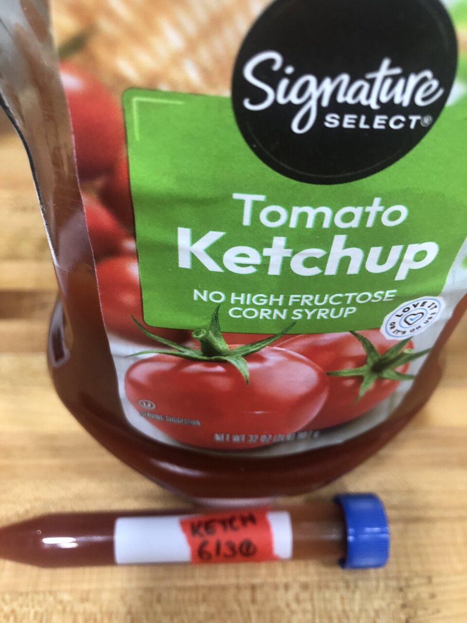 Jar of Signature Select tomato ketchup with a labelled sample tube in front.
